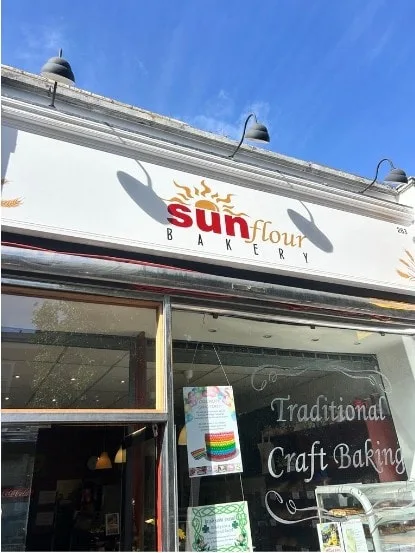 The new white Sun Flour Bakery sign with a sun logo above the shop window on Caledonian Road